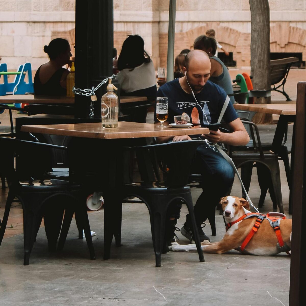 A man sitting on a dog-friendly restaurant patio with his dog