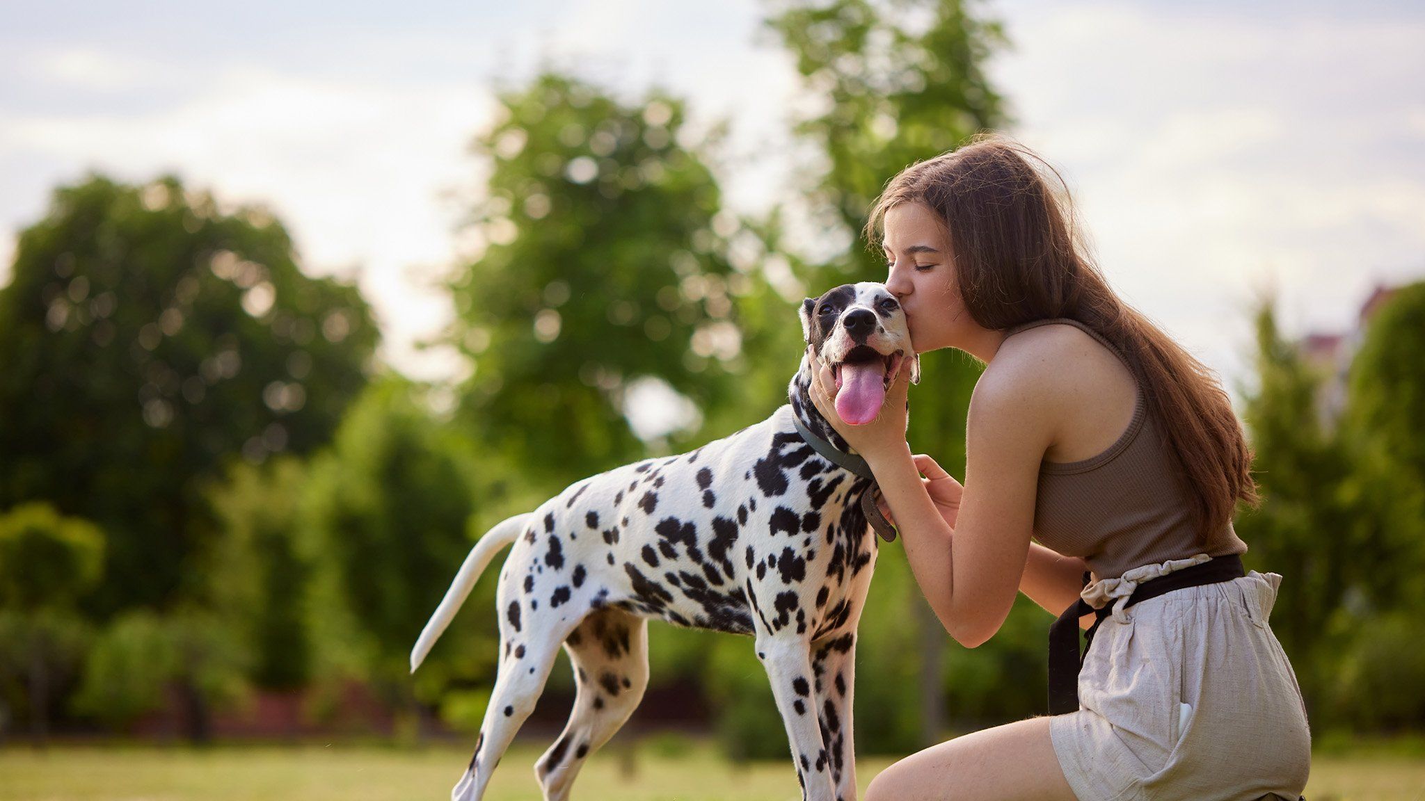 young woman kissing beautiful dalmatian dog